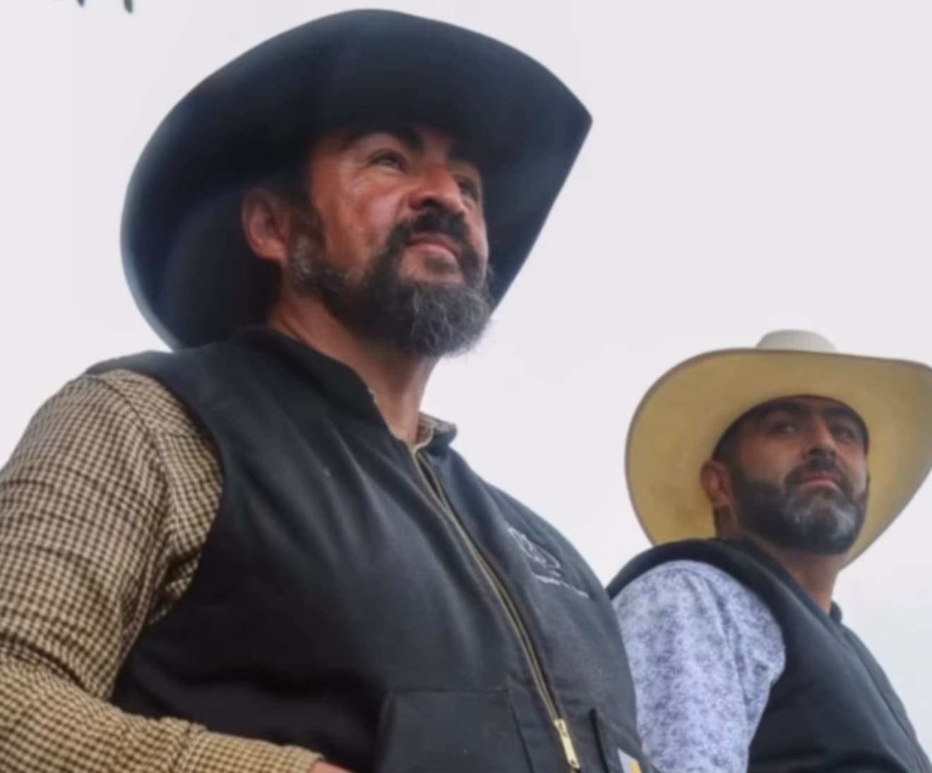 Two riders in cowboy hats looking out over the crowd